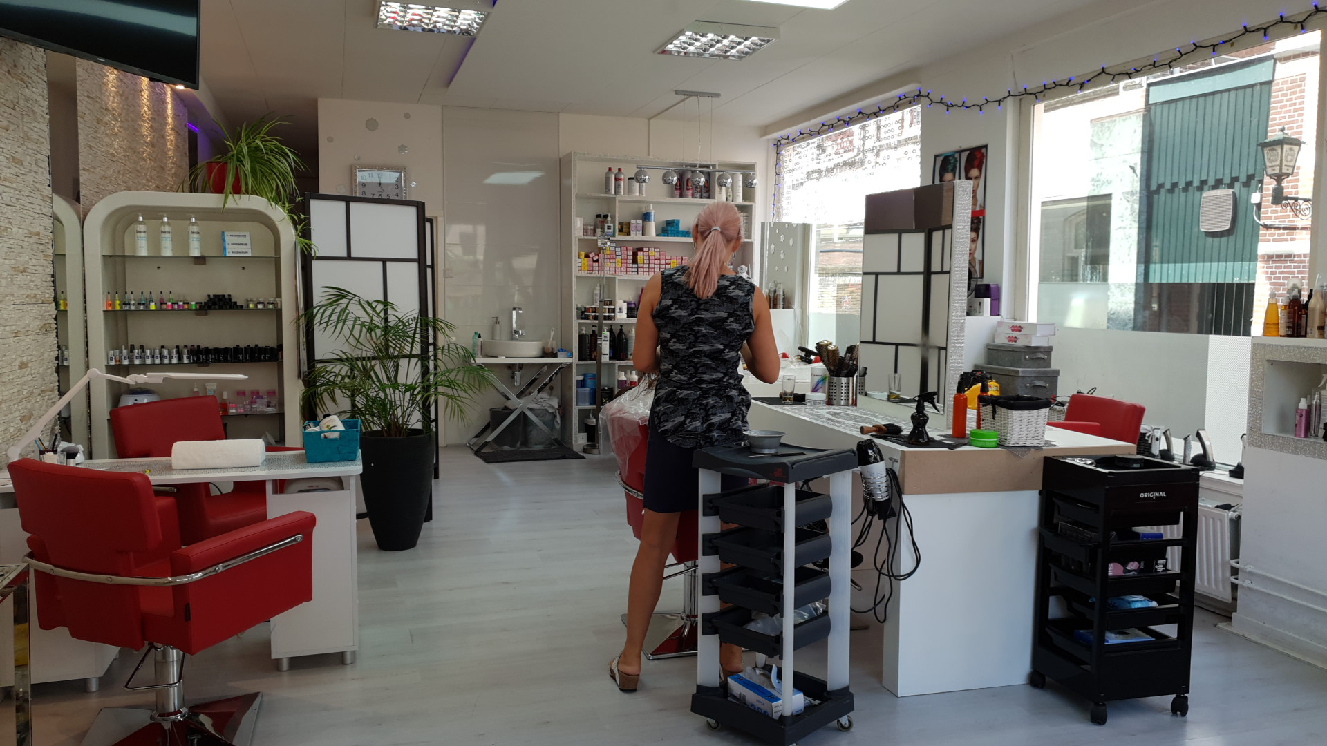 Aan de balie van Kapsalon Dora, met de rode stoelen en de werkplekken