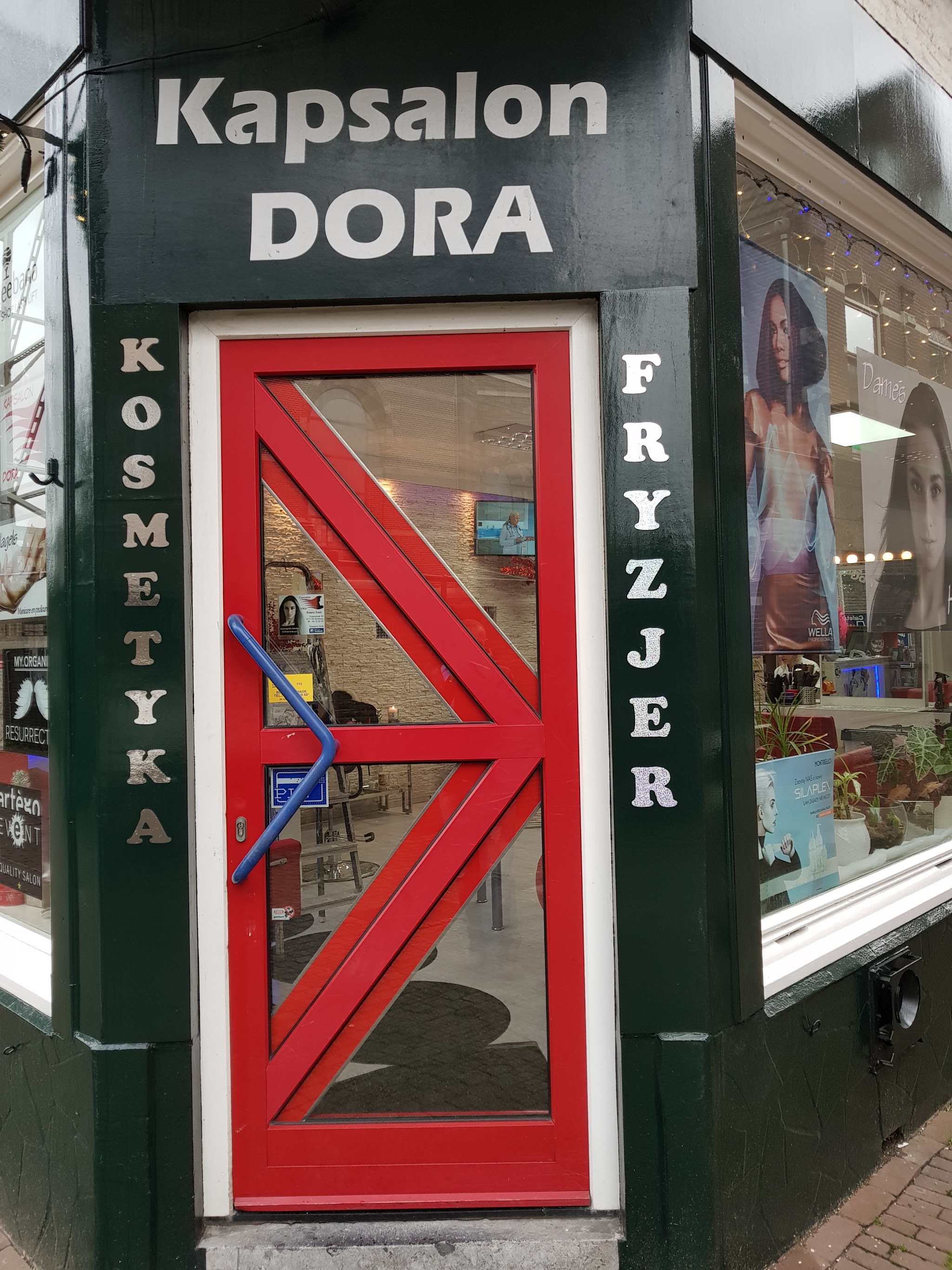 De rode deur van Kapsalon Dora met de letters KOSMETYKA en FRYZJER ernaast